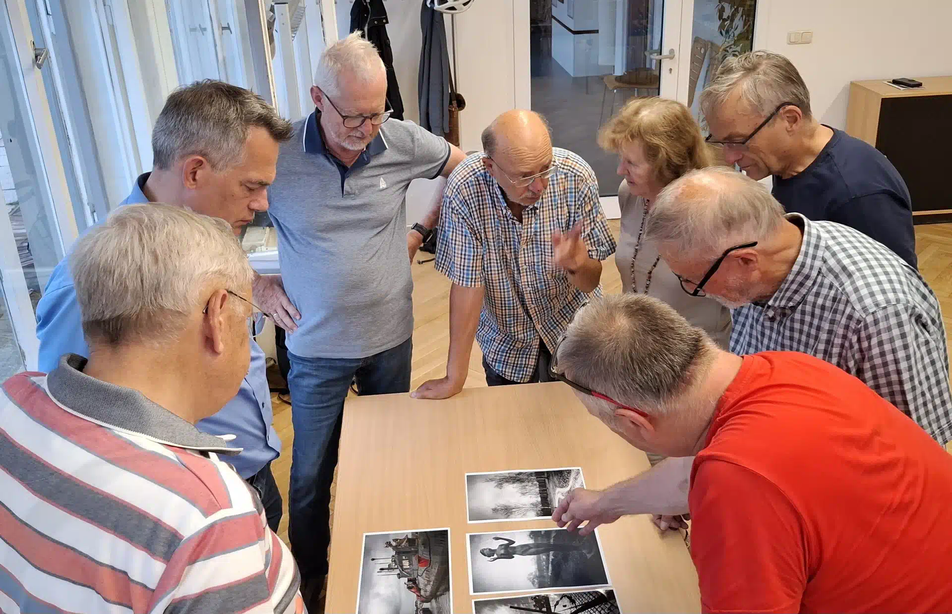 Mitglieder des Fotoklubs diskutieren gemeinsam Fotografien während eines Klubabends